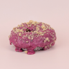 Purple donut with crumb topping on a pink background