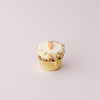 cupcake topped with icing and a carrot design, garnished with chopped walnuts
