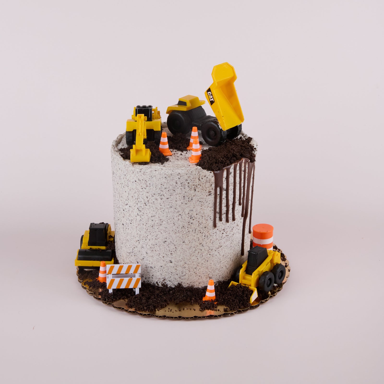 cookies and cream cake with drip, construction cones and truck decorations