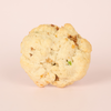 Single savory scone on a light pink background, bits of bacon and green onions throughout